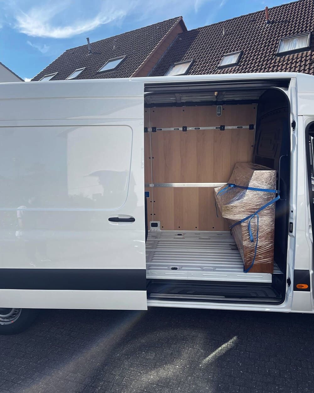 Sorgfältig eingepacktes und mit Spanngurten gesichertes Möbelstück im Laderaum eines Sprinters