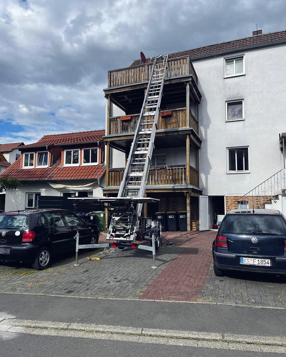 Möbellift der Umzugshelden Hessen an einem Mehrfamilienhaus in Kassel, die Leiter reicht bis zum obersten Balkon